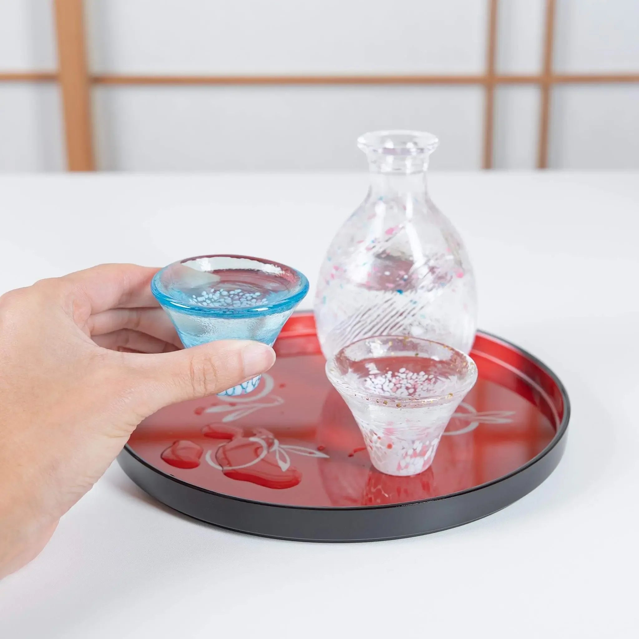 Handmade Japanese sake set in use with sakura and Mount Fuji design, glass cups and bottle on serving tray