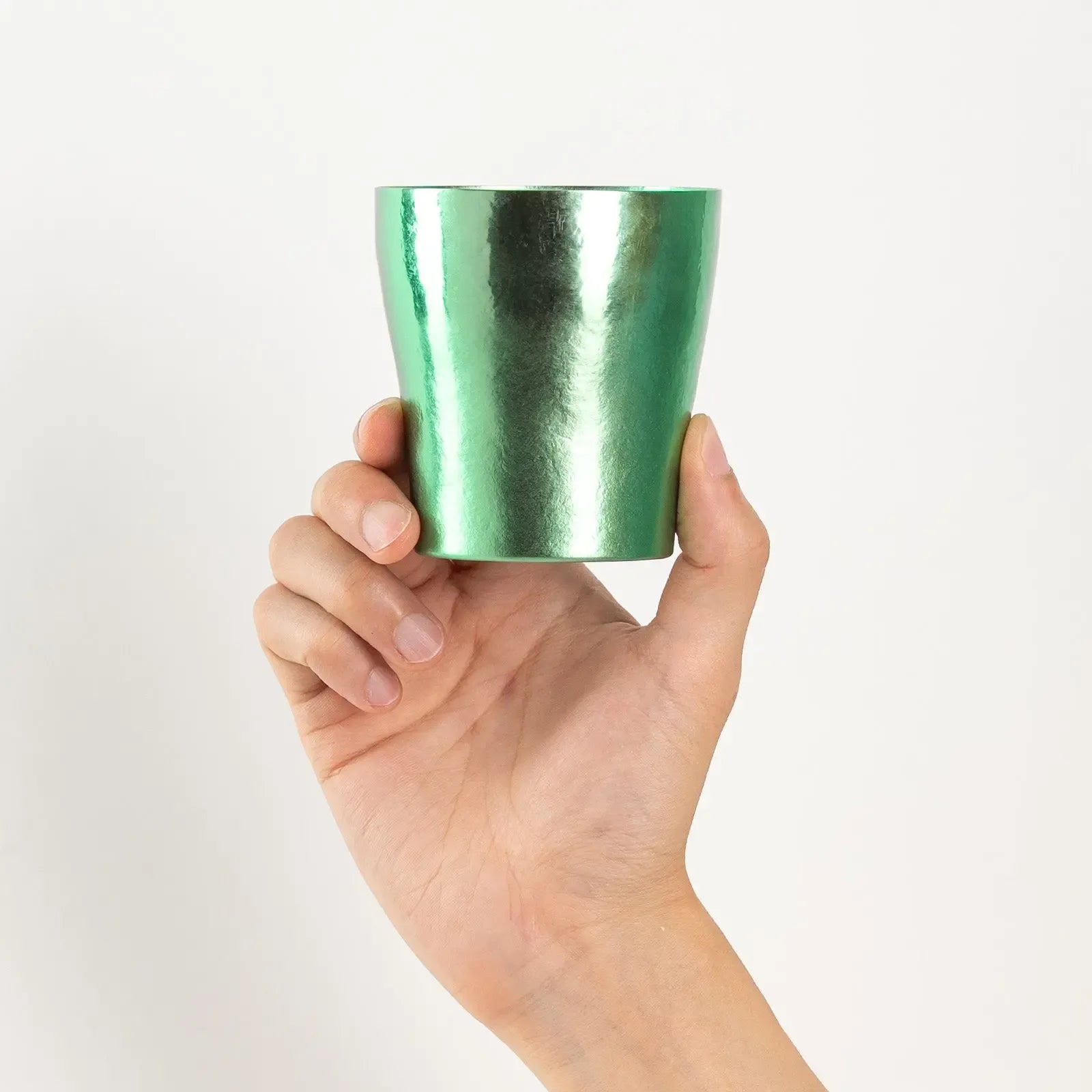 Green titanium tumbler held upright by hand