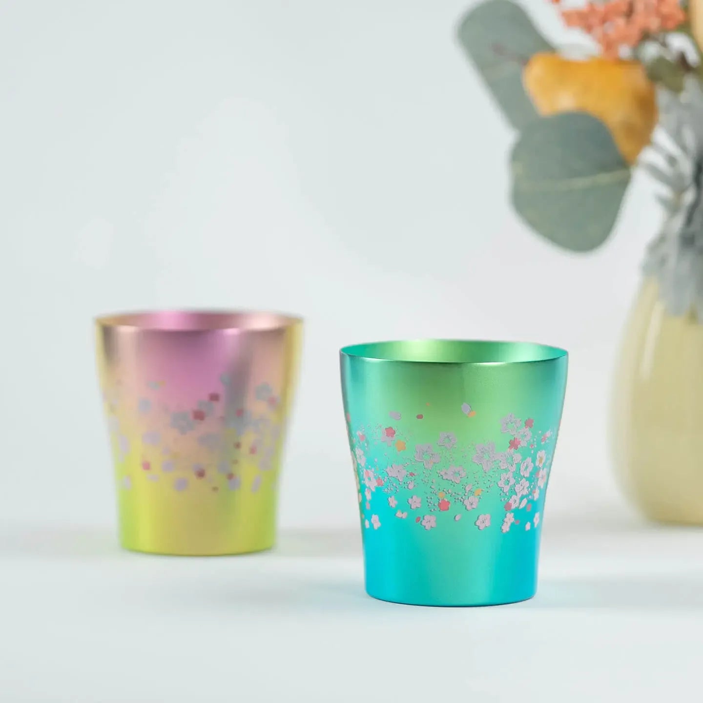 Front view of the HORIE Sakura Saku titanium tumbler pair (Pink and Green) sitting on a table.