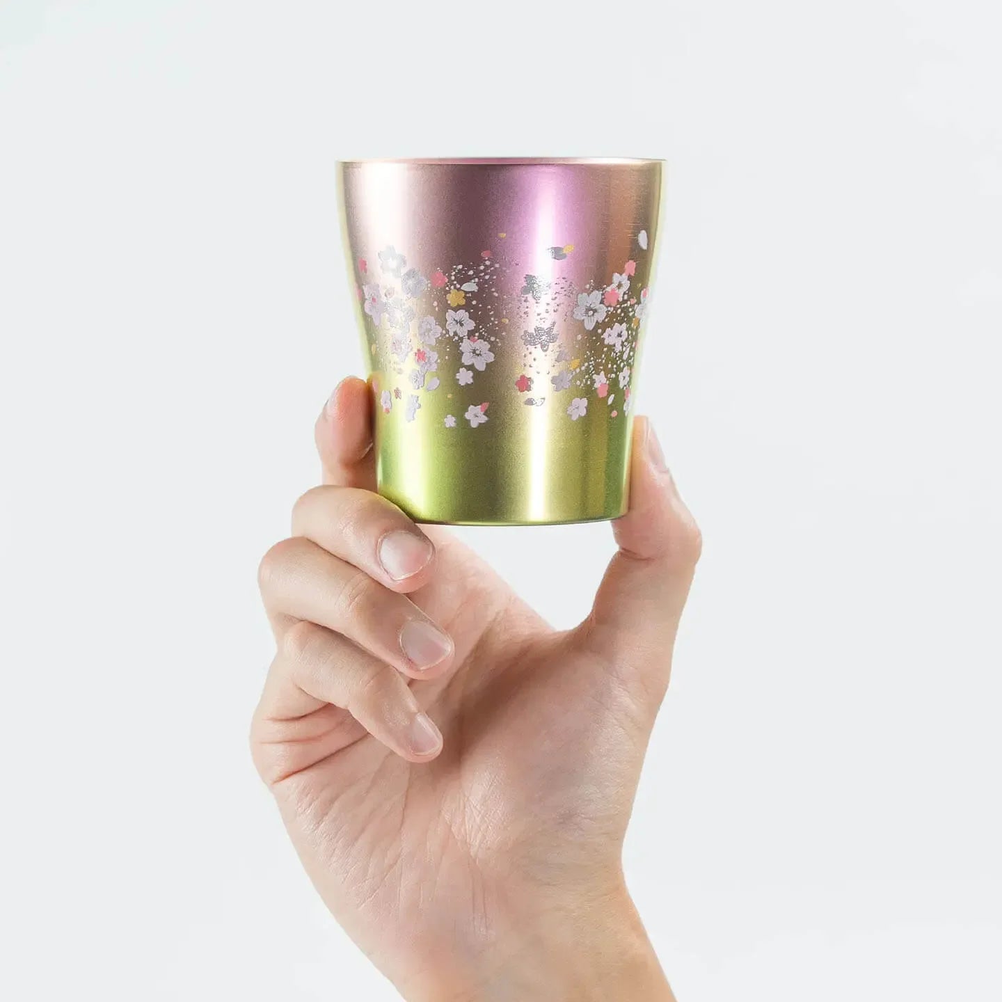 A hand holding the front of the pink HORIE Sakura Saku tumbler to show the 'Sakura Saku' pattern.
