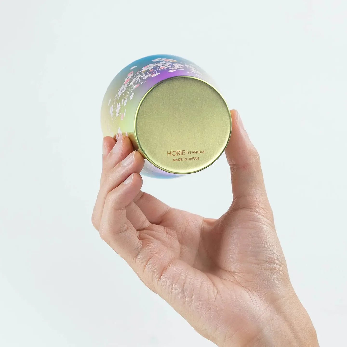 A hand holding the pink HORIE tumbler to show its base.