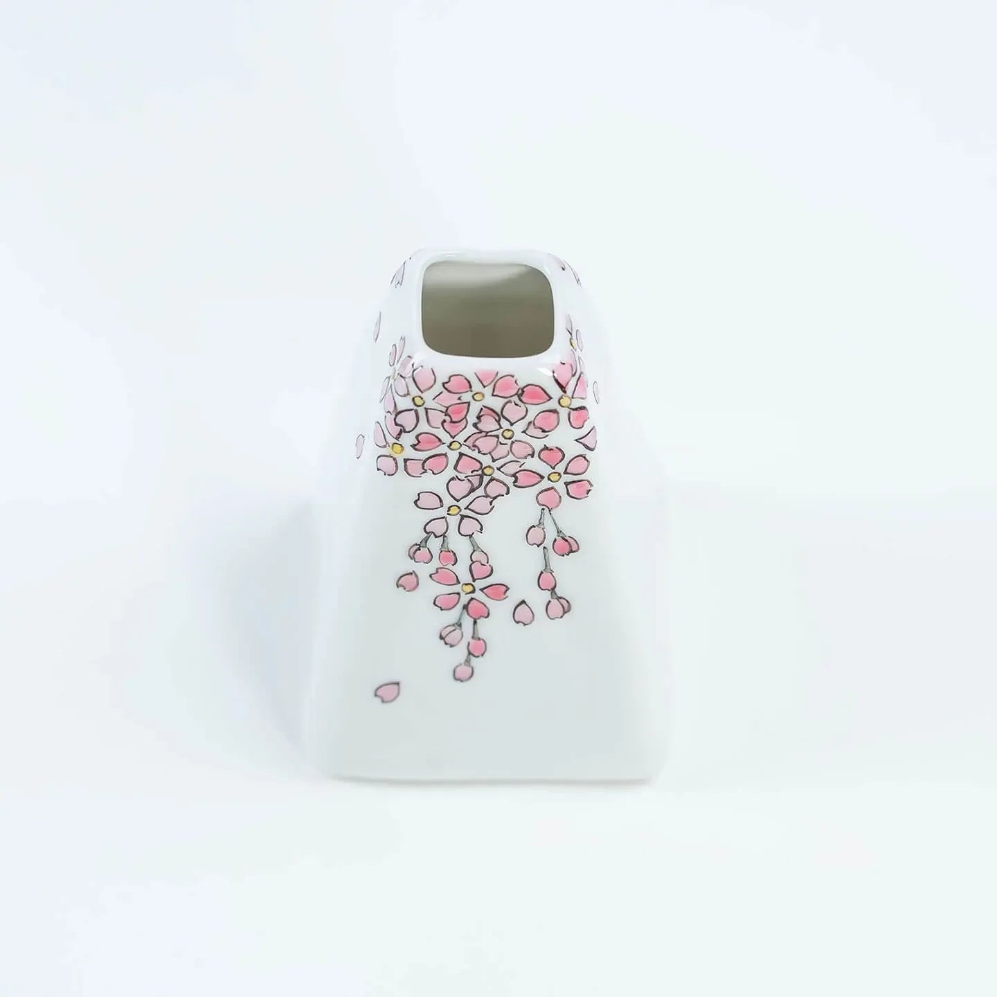 A white Kutani-yaki ceramic vase in the shape of Mt. Fuji with a pink cherry blossom pattern.