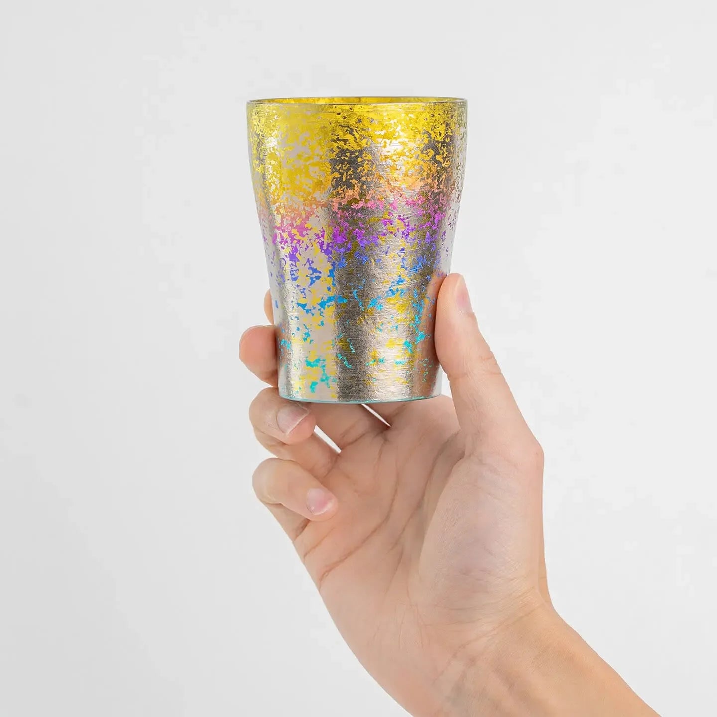 Hand holding the Taiko Series Rainbow Titanium Tumbler for size reference.