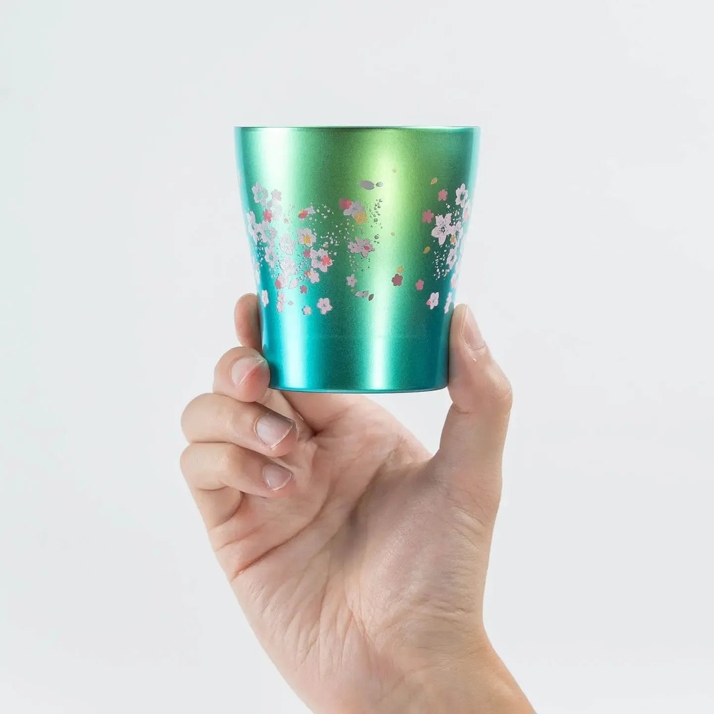 A hand holding the green HORIE Sakura Saku tumbler (250ml) to show its scale.