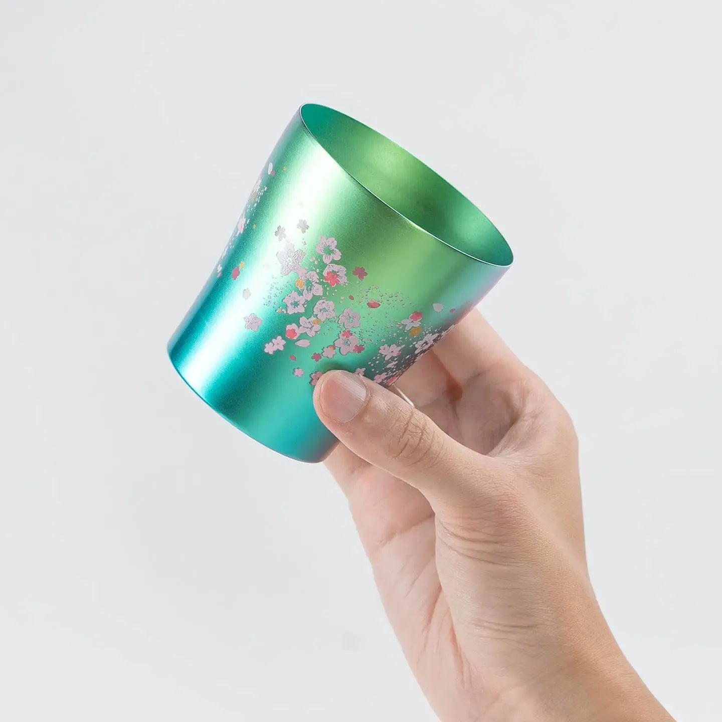 A hand holding the side of the green HORIE Sakura Saku tumbler to show its profile.