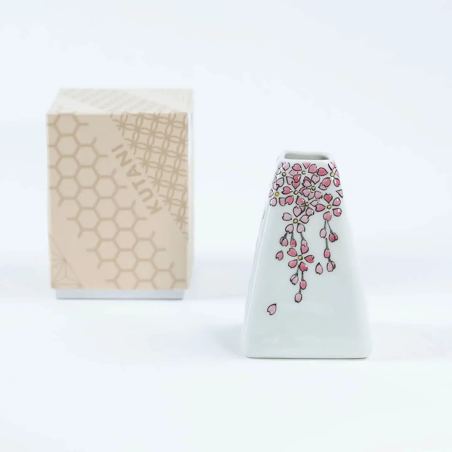 A white Kutani-yaki ceramic vase in the shape of Mt. Fuji with a pink cherry blossom pattern.