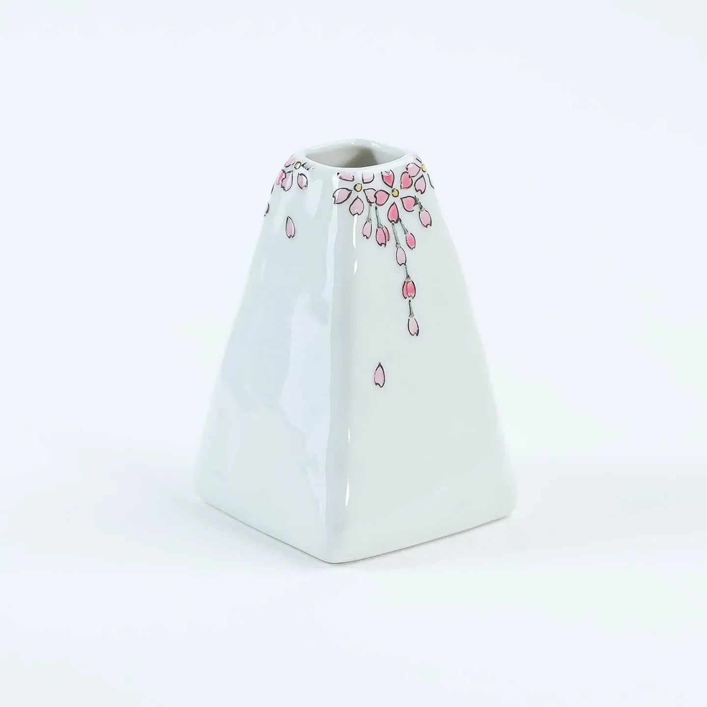 A white Kutani-yaki ceramic vase in the shape of Mt. Fuji with a pink cherry blossom pattern.